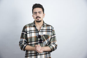 Portrait of bearded man with glasses standing over white wall. High quality photo